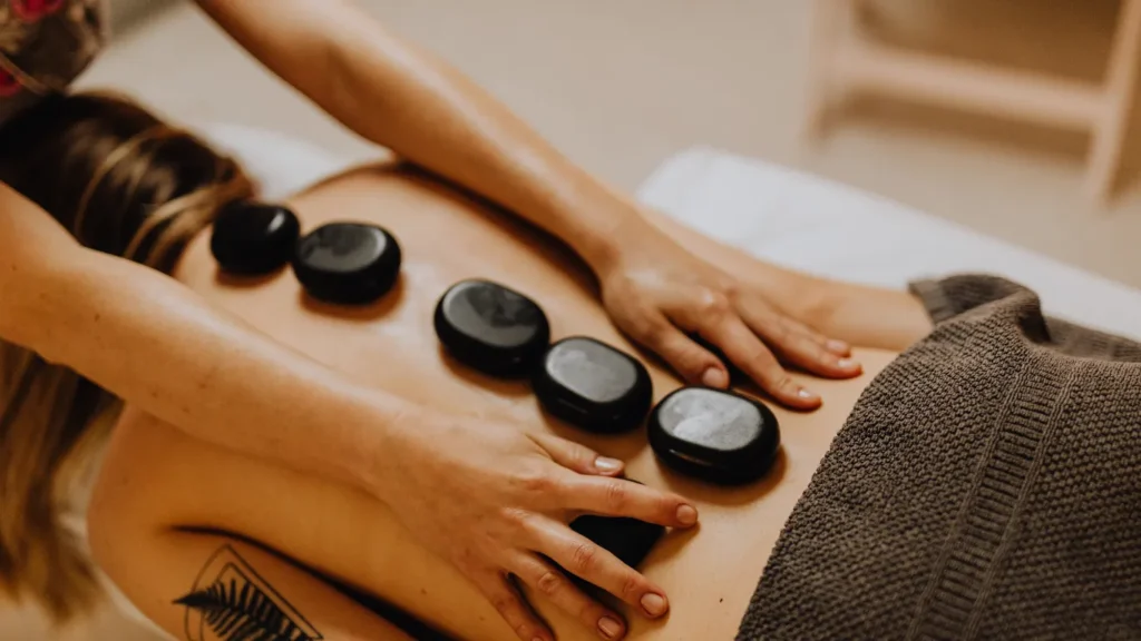 Therapist using heated stones in circular motion on shoulders